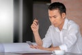 Selective focus of Casual young business man using mobile smart phone with pen and coffee blurred background Royalty Free Stock Photo