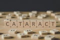 Focus of cataract lettering on cubes surrounded by blocks with letters on wooden surface isolated on black