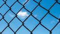 Selective focus on chain link fence with blue sky and clouds in Royalty Free Stock Photo