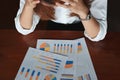 Selective focus on charts on the workplace with upset stressed Asian business woman.
