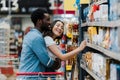 Focus of cheerful african american man standing with asian woman smiling near groceries in supermarket Royalty Free Stock Photo
