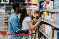 Focus of cheerful african american man standing with cheerful asian woman pointing with finger at groceries in Royalty Free Stock Photo