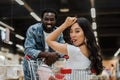 Focus of cheerful asian girl sitting in shopping cart and showing tongue near african american man Royalty Free Stock Photo