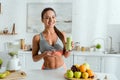 Focus of cheerful girl with sportswear gesturing and holding glass with tasty smoothie