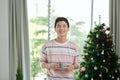 selective focus of cheerful man holding cup near christmas tree in living room
