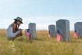 Focus of child covering face while sitting near headstones with american flags