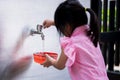 Selective focus. Child fill a bowl with water for making watercolor art, handicrafts. On the back of a 4 year old girl.