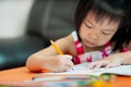 Selective focus of child hand coloring on workbook. Student kid learning. Kindergarten girl doing homework on orange table. Royalty Free Stock Photo