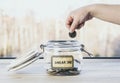 Selective focus on child hand  put euro coin in swear jar. Royalty Free Stock Photo