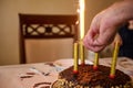 Selective focus on chocolate cake and hand turning on burning candles lighting burning candles on birthday