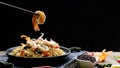 Selective focus at chopstick pickup shrimp with stir fry instant noodles spicy seafood in black plate with various spices on black