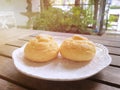 Selective focus of Choux cream in white plate on wooden table with sun shining in cafÃÆÃÂ©