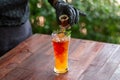 Selective focus. Clear glass. Orange juice drink with ice in the glass. And the hand of shopkeeper wearing black gloves pouring a Royalty Free Stock Photo