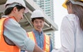 Selective focus and close up on asian male civil engineer face smiling, wearing safety helmet, meeting, discussing about building