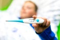 Selective focus Close up ill young child or schoolboy, lying in bed shows a 38.6 c thermometer, height of his fever Royalty Free Stock Photo