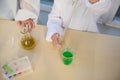 Selective focus: kids performing chemical experiments, using graduated pipette, beaker, test tubes at chemistry class