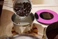 Close-up putting dark chocolate chips into a metal bowl for melting chocolate and preparing cake cream. Selective focus Royalty Free Stock Photo