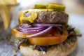 Selective focus close-up shot of a vegan burger bun with plant-based cheese, onion and tomato Royalty Free Stock Photo