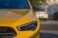 Selective focus closeup of a bright yellow Mercedes-Benz car driving