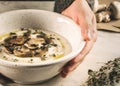 Selective focus closeup of a female's hands holding a bowl of mushroom soup