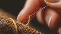 selective focus closeup of hands with needle sewing thread in fabric