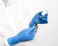 Selective focus closeup of a pair of hands wearing gloves while holding a syringe and a vaccine