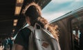 Selective focus closeup shot of a female with ponytail wearing gray backpack at a train station