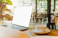 Selective focus on coffee cup and laptop on wooden table in blur background. Royalty Free Stock Photo