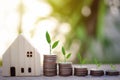 Selective focus of coins stack and plant growing with house model for saving money to buy a home. Royalty Free Stock Photo