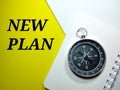 Selective focus compass on a notebook with word NEW PLAN on a white and yellow background.Business concept. Royalty Free Stock Photo