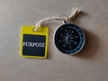 Selective focus of compass and wooden board with written text PURPOSE on a wooden background.Shot were noise and film grain.