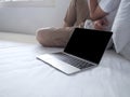Selective focus on computer laptop against stressed upset young Asian man in depression on the bed