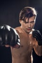 Selective focus of concentrated boxer in boxing gloves training and looking at camera.