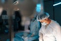 Selective focus of cooperating team of surgeons processing surgical operation in dark operating room modern hospital Royalty Free Stock Photo