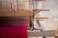 Selective focus of cotton fabric on wooden weaving machine. Homespun fabric process. Cotton fabric weaving in vintage weaver