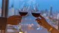 Selective focus of couple  hand with wine glasses have a romantic dinner on the rooftop with city as bokeh background Royalty Free Stock Photo