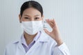 Selective focus on Covid-19 vaccines vial bottle in hand of Asian young doctor woman wear face mask, white gown and smiling