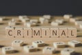 Focus of criminal lettering on cubes surrounded by blocks with letters on wooden surface isolated on black