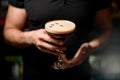 Selective focus on crystal glass with tasty foamy cocktail decorated with coffee beans in male hands. Royalty Free Stock Photo