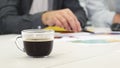 Close up of a cup of coffee on the table businesspeople working on the background