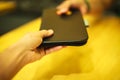 Selective focus customer hand receive bill payment receipt in black leather folder holder tray on yellow wooden table background