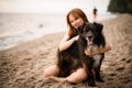 Selective focus on cute dog on the beach. Smiling young woman hugs the dog.