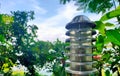 Selective focus of decorative streetlamp with blurred green trees and sky in background