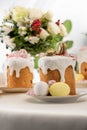 Selective focus of delicious easter cake with golden french macaroons and meringue on icing near floral bouquet and eggs