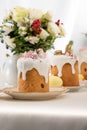 Selective focus of delicious easter cakes with golden french macaroons and meringue on icing near floral bouquet.