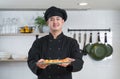 Selective focus on delicious sushi on plate in hand of young handsome Asian chef with black uniform and hat, Japanese food Royalty Free Stock Photo