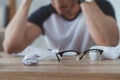 selective focus of depressed student at table with crumpled papers and eyeglasses