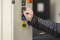 Selective focus. Detailed view of an arm and hand from a blue-collar working pushing on a button from a hydrolic car lift.