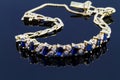 Selective focus of diamond with sapphire bracelet on glossy dark