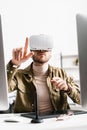 Selective focus of digital designer in virtual reality headset pointing with finger near graphics tablet and computers Royalty Free Stock Photo